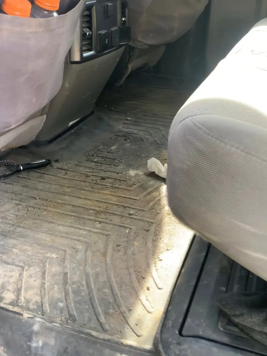 Pickup back-seat floor liner covered in mud and dirt before an interior detail